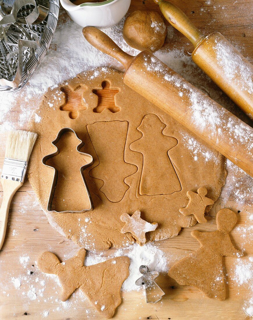 Ausgerollter Lebkuchenteig mit Ausstechförmchen und rohen Lebkuchenmännchen