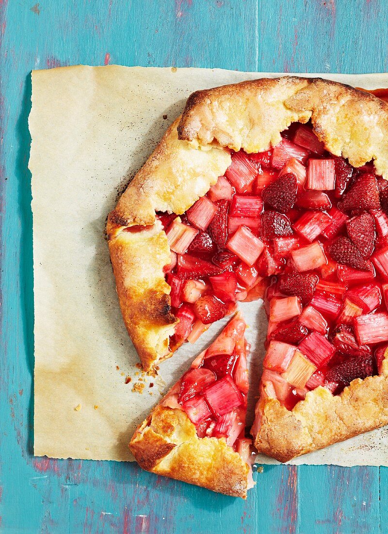 Angeschnittener Erdbeer-Rhabarber-Kuchen auf Backpapier