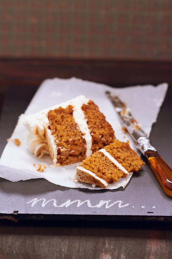 A slice of carrot cake with cream cheese frosting, cut in two pieces