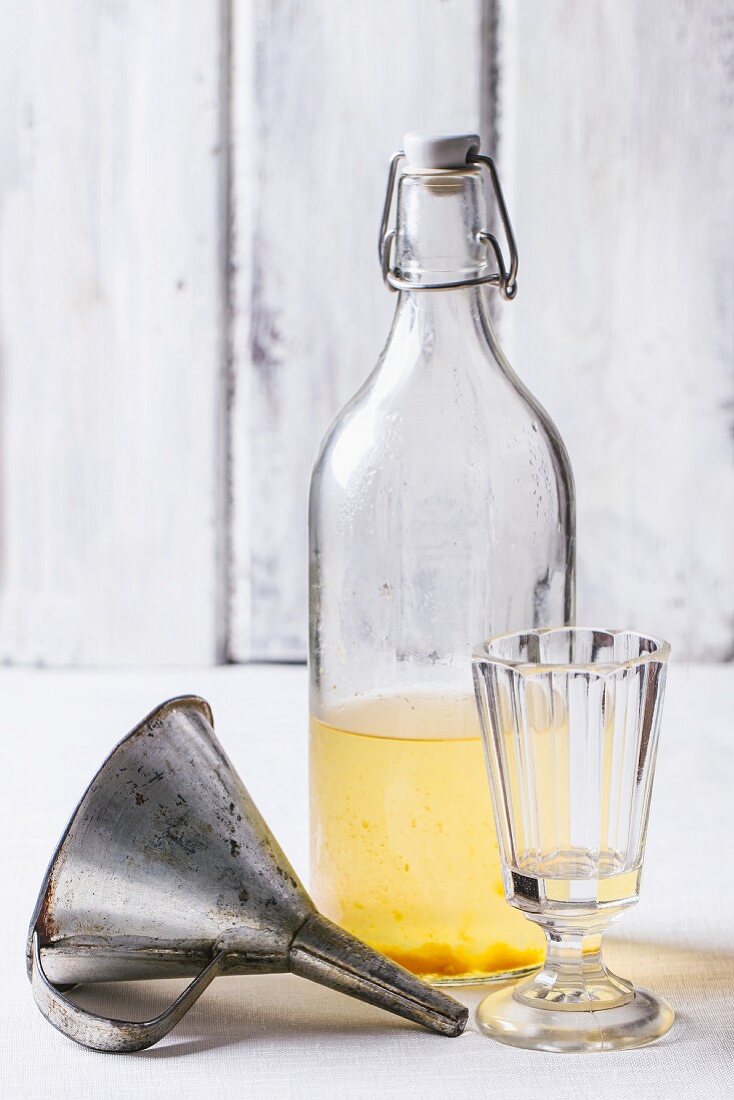 A bottle of homemade liqueur with a vintage glass and a funnel