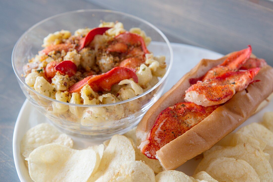 Grilled lobster on macaroni and cheese, a lobster roll and potato crisps