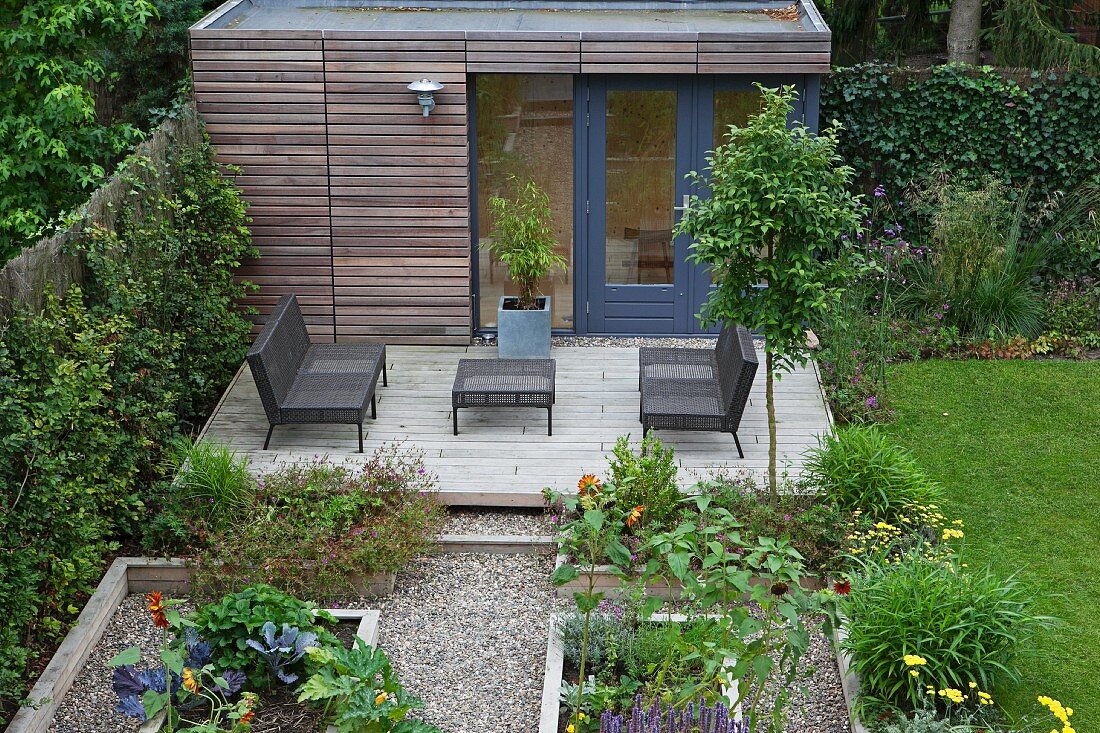 Hochbeete vor modernem Terrassenplatz mit Outdoor-Möbeln und Gartenhäuschen