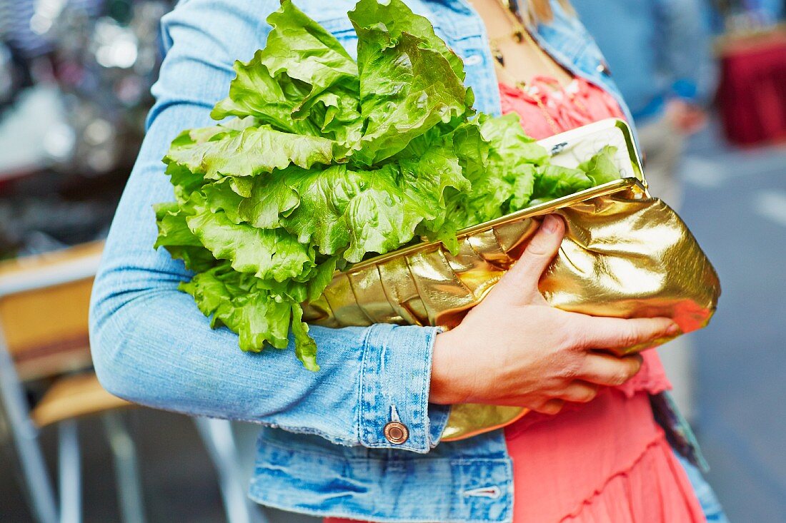 A woman carrying a lettuce in her handbag