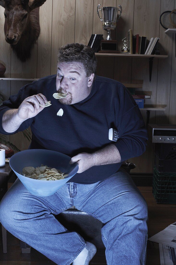 Mann isst Kartoffelchips vor dem Fernseher