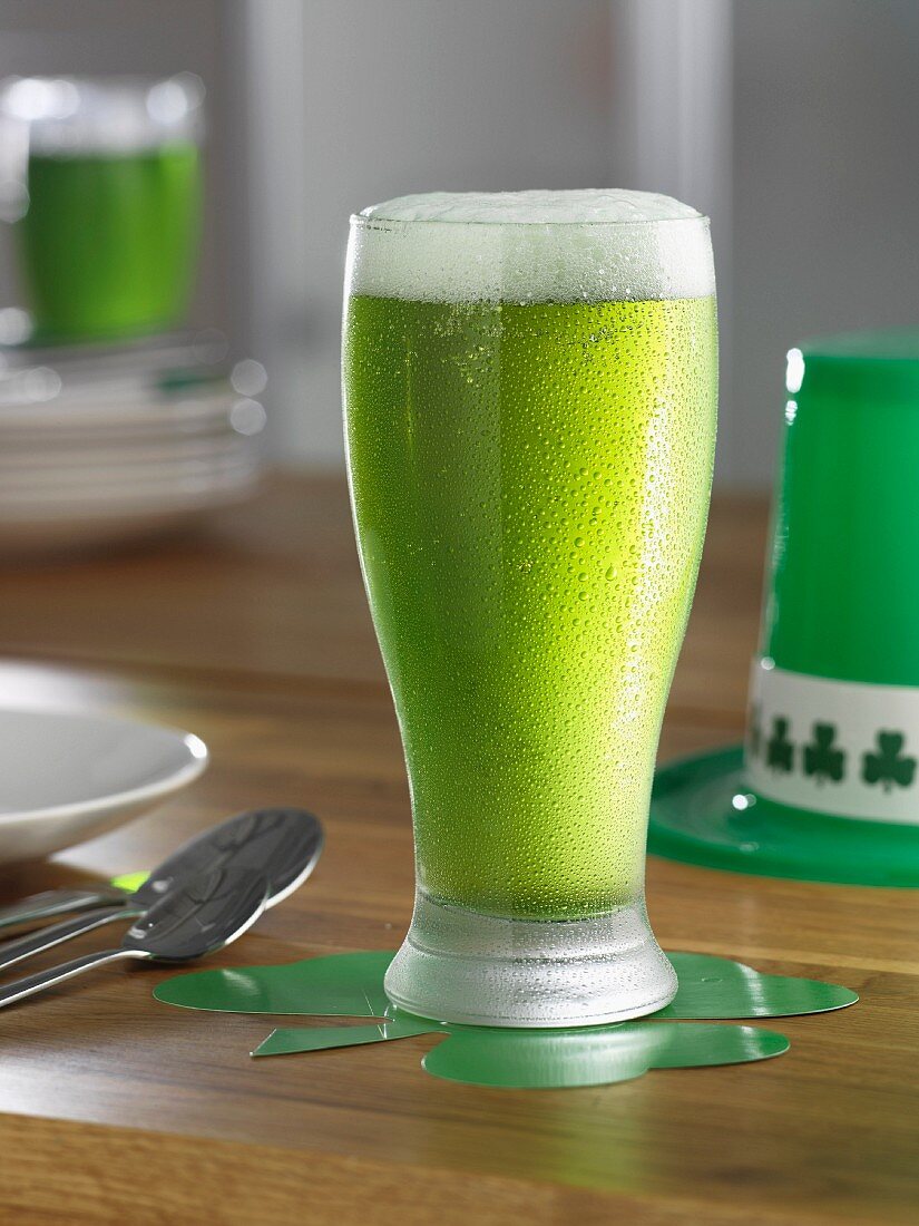 Ein Glas grünes Bier am Tisch