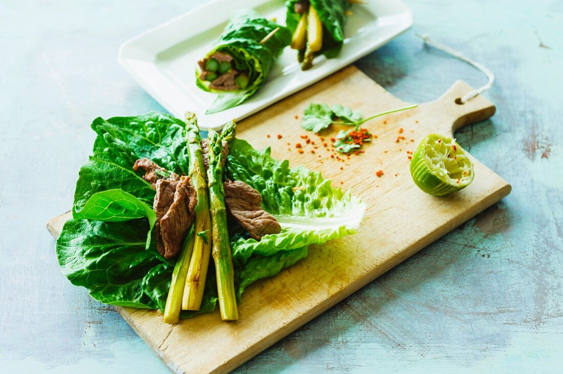 A lettuce wrap with green asparagus and strips of beef steak
