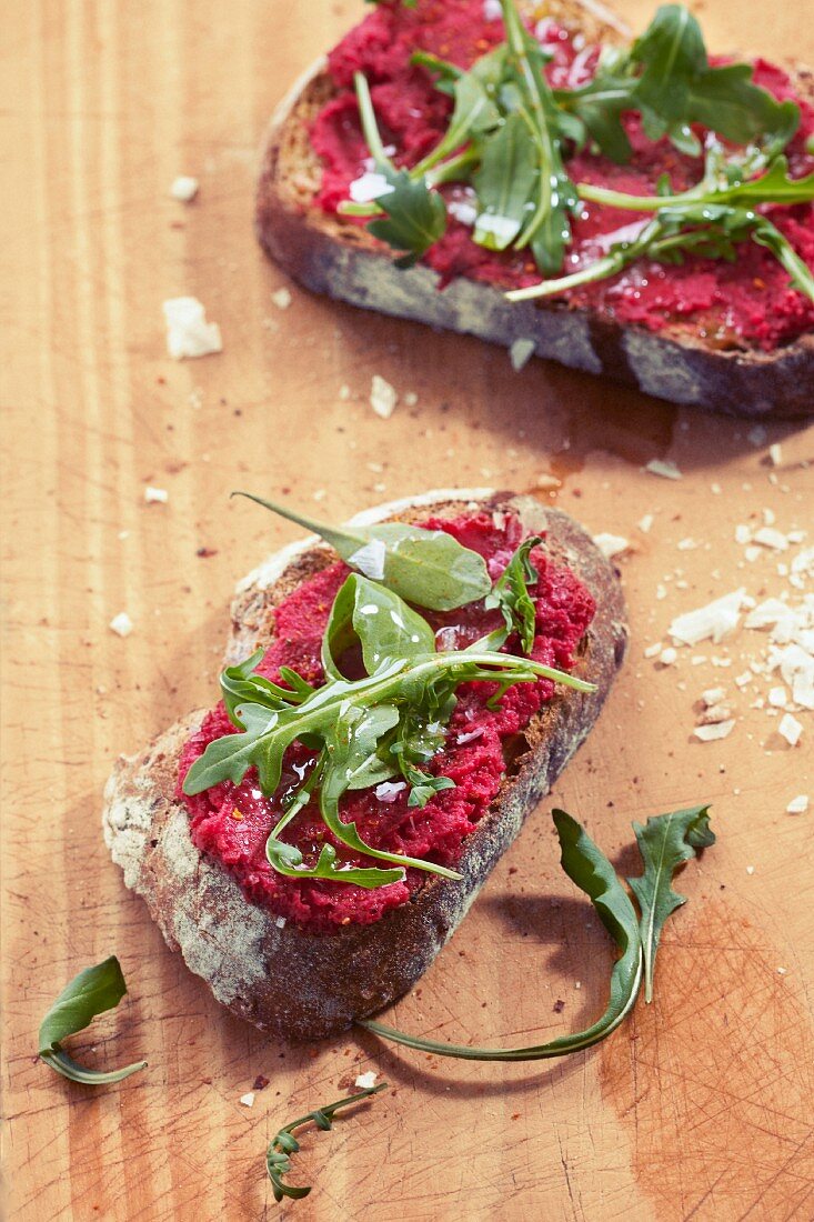 Slices of bread topped with beetroot spread and rocket
