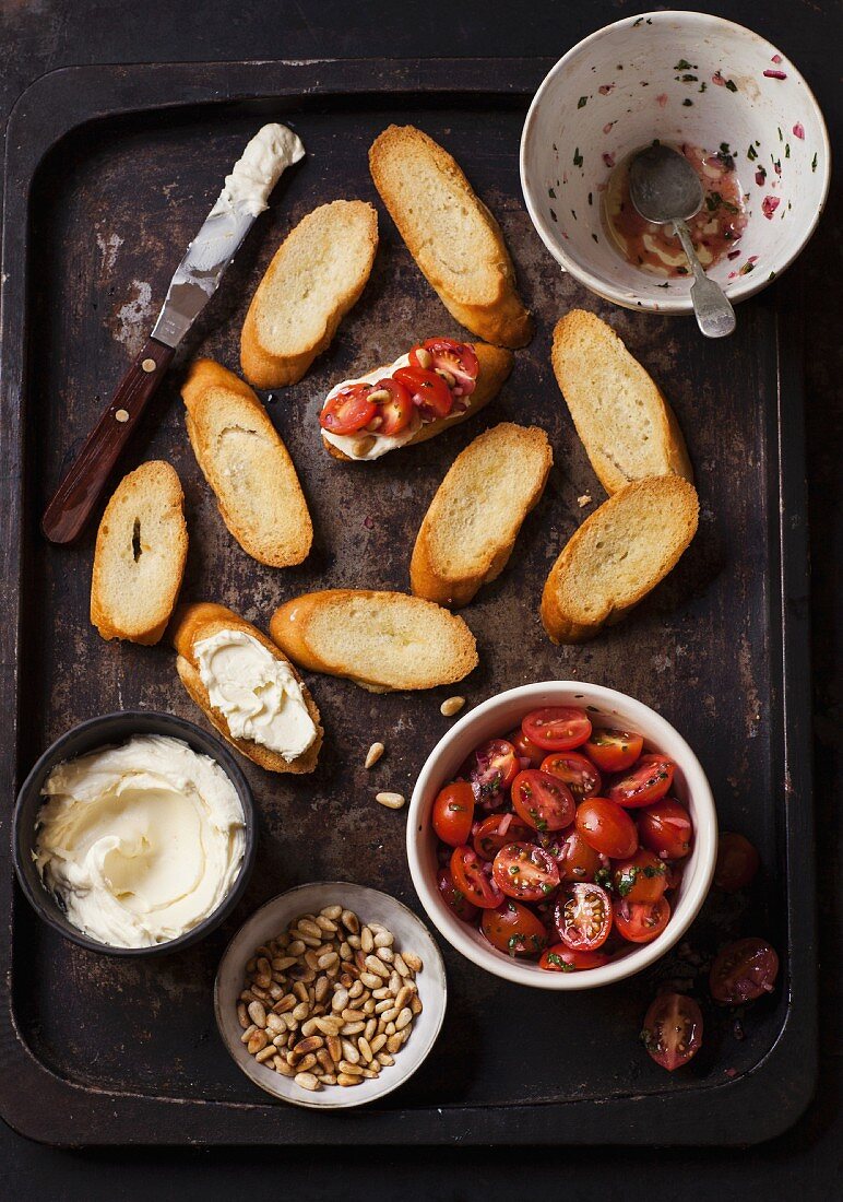 Ingredients for bruschetta with tomatoes, whipped goat cheese and pine nuts