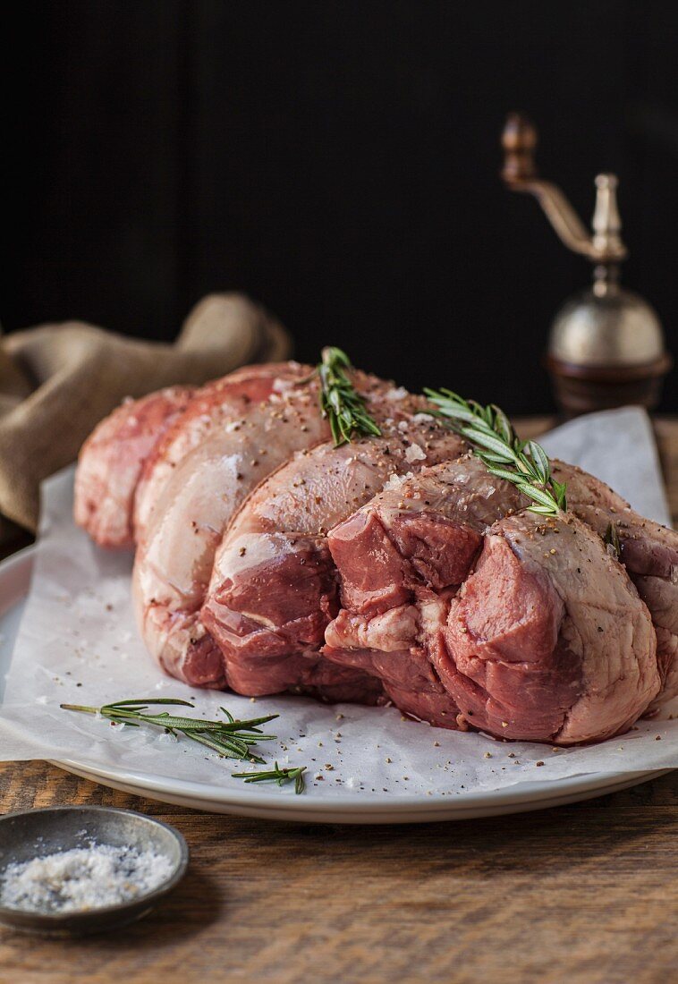 A deboned raw leg of lamb with salt and rosemary