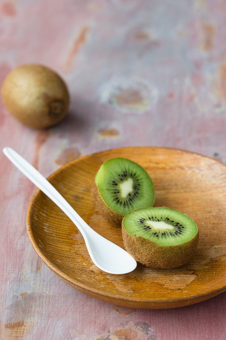 A halved kiwi on a wooden plate
