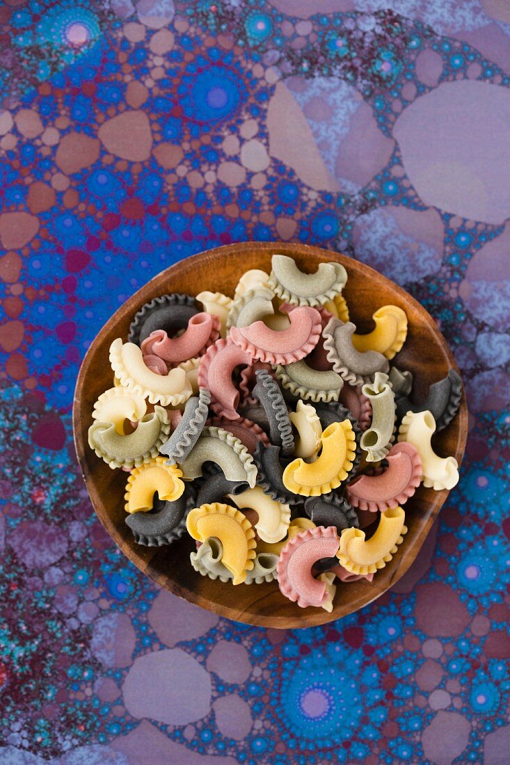 Colourful pasta on a wooden plate
