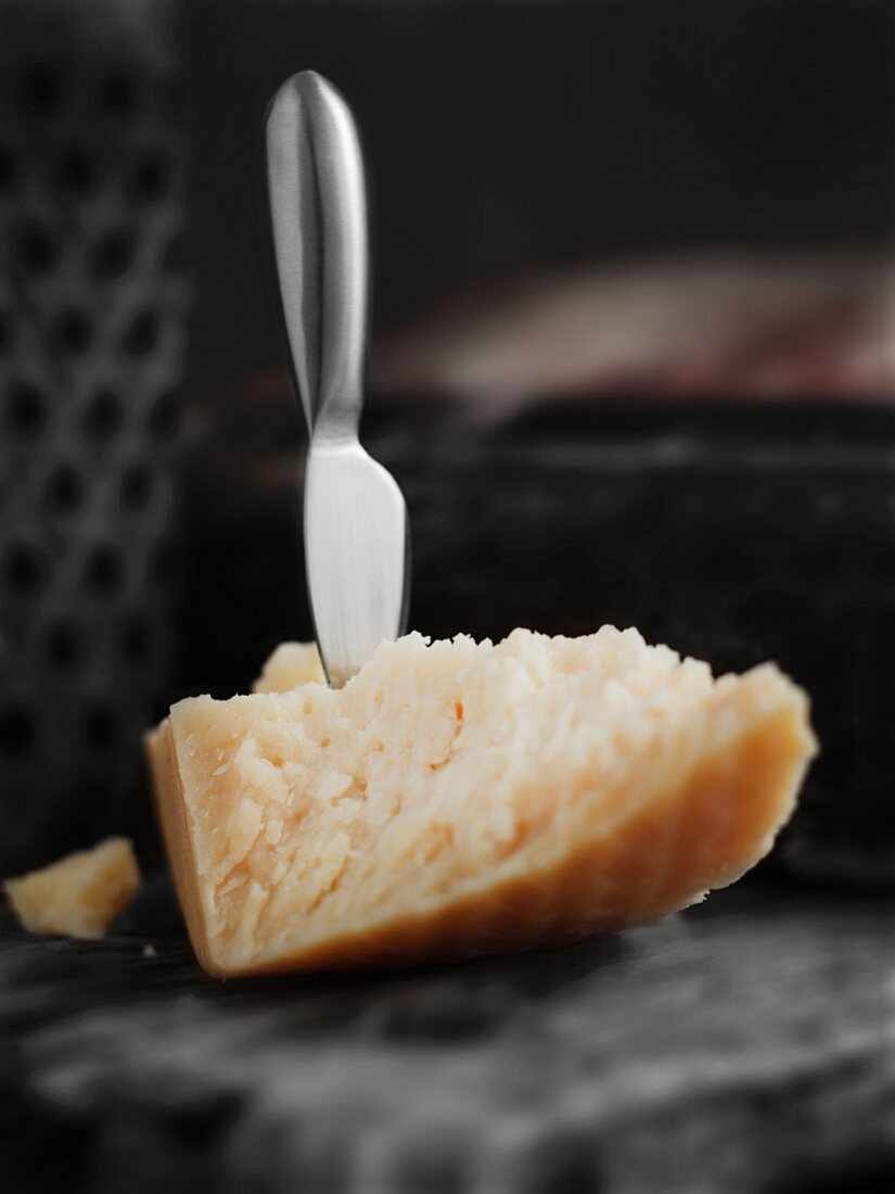 A piece of Parmesan cheese with a cheese knife