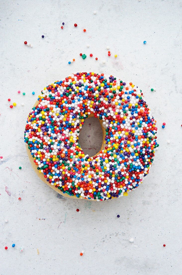 A doughnut with colourful sugar sprinkles (seen from above)