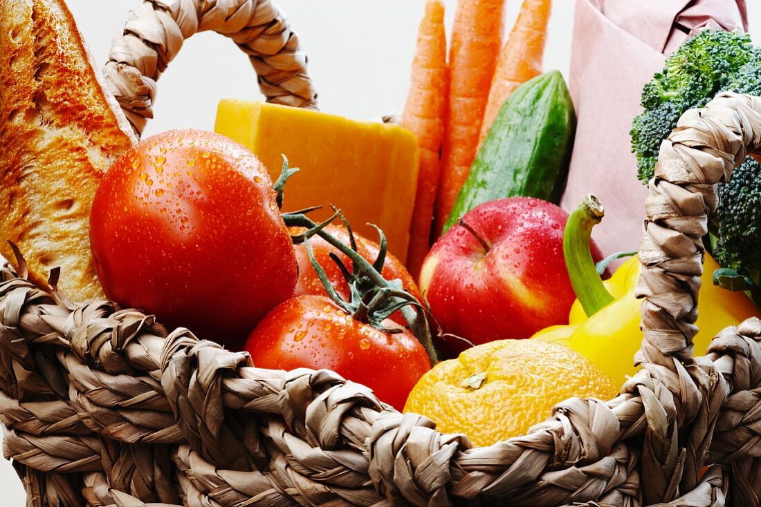 Vegetables, fruit, cheese and baguette in a basket