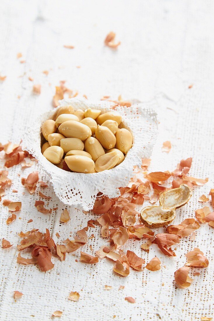 Geschälte Erdnüsse in einer Schale, daneben Schalenreste
