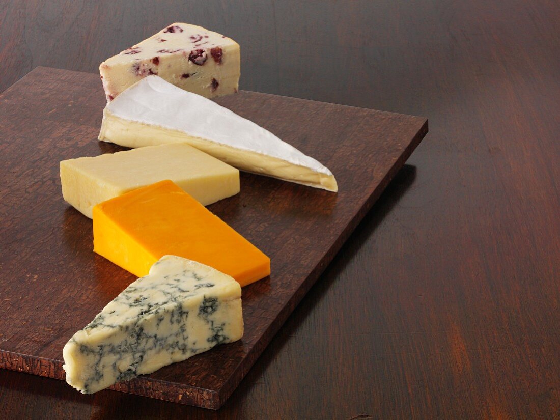 Various wedges of cheese on a wooden board