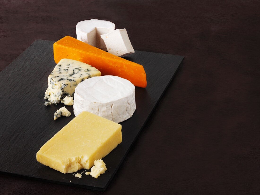 A selection of cheeses on a black platter