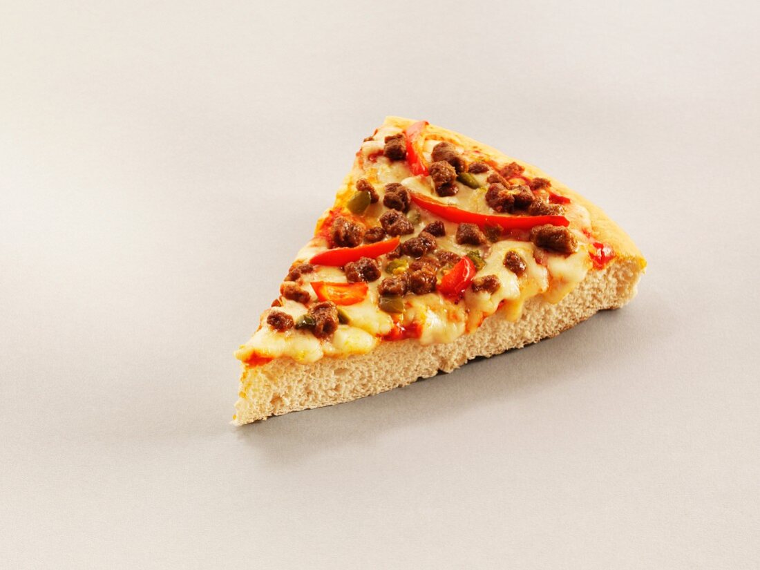 A slice of pizza with chilli peppers, beef and cheese