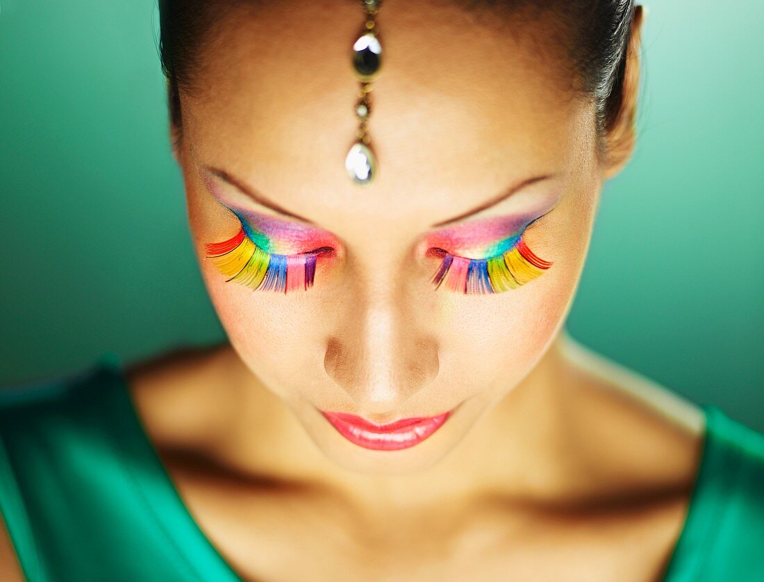 A young woman with colourful eyelashes and glittering head jewellery