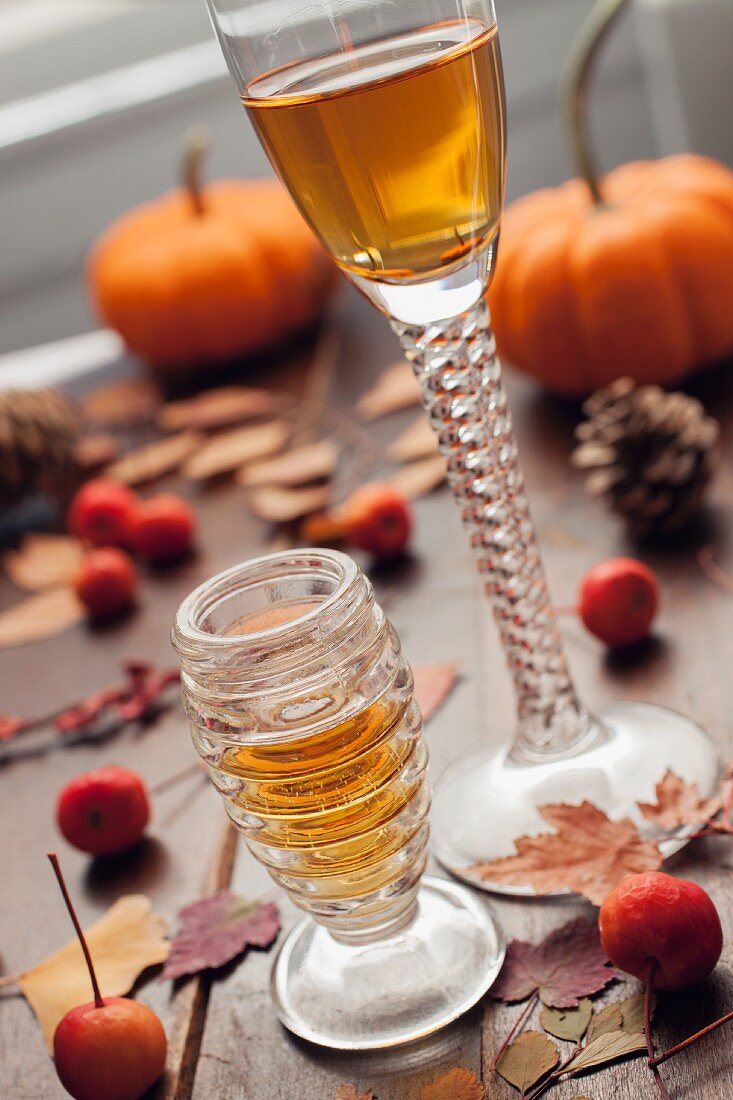 Zwei Gläser Dessertwein mit Herbstblättern und Beeren auf Holztisch