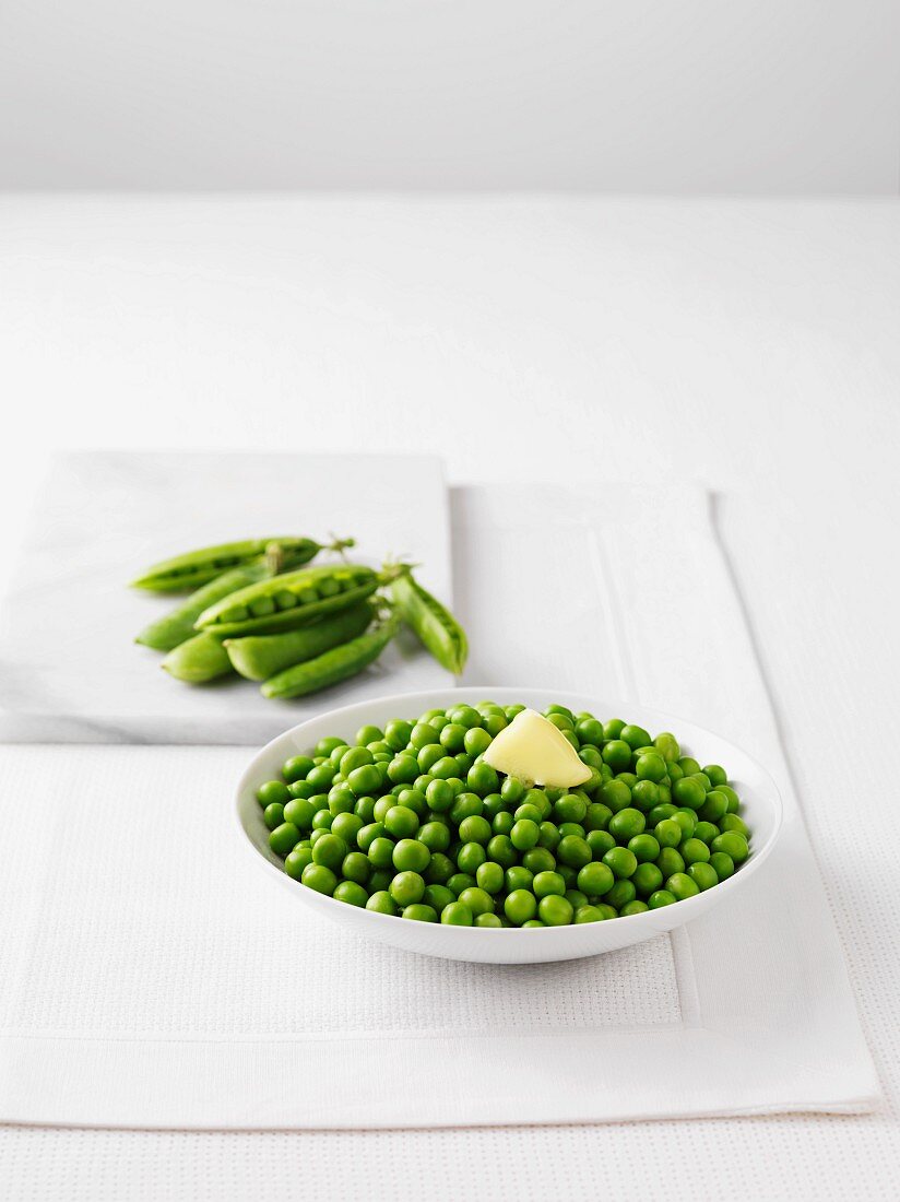 Fresh peas and a bowl of boiled peas with butter