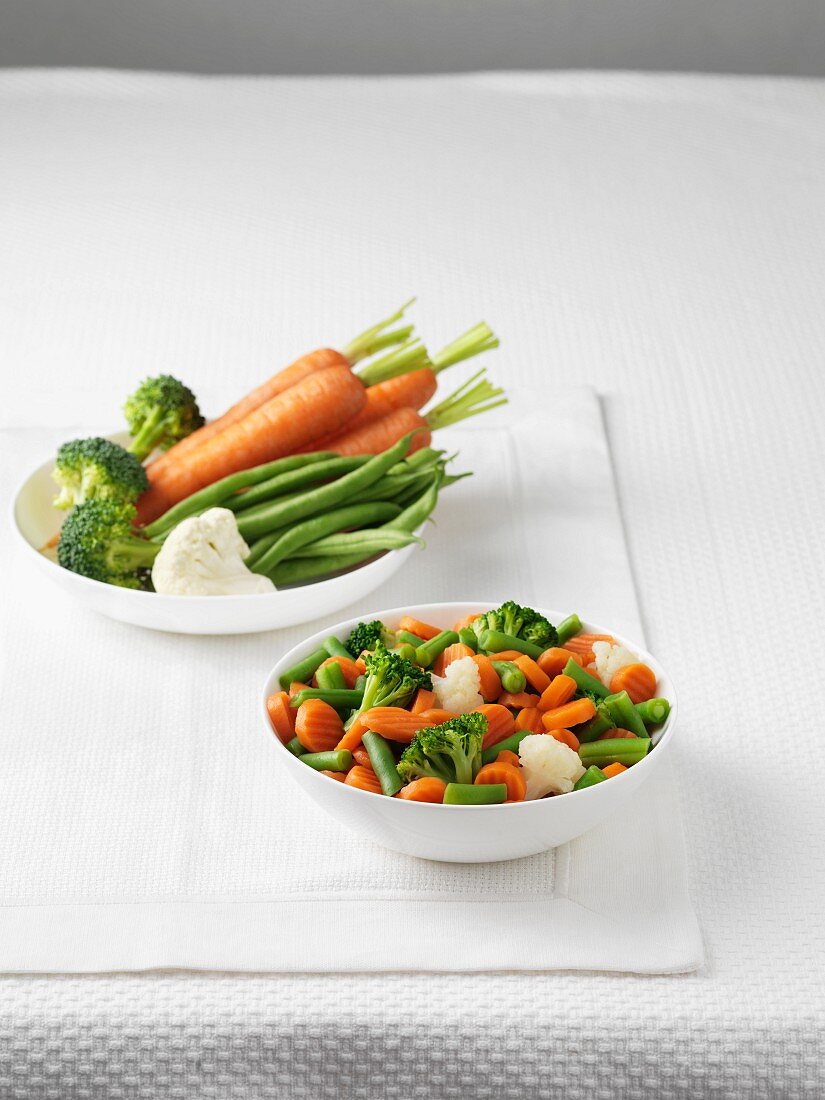 Fresh vegetables and a bowl of boiled mixed vegetables