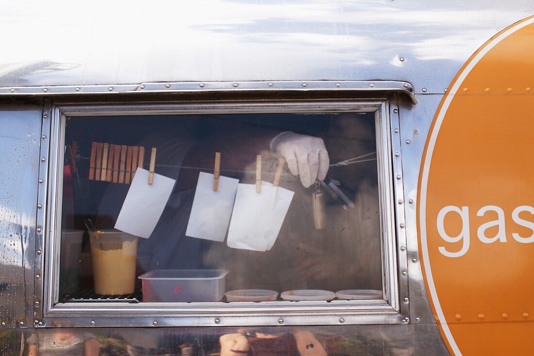 Fenster eines Imbisswagens mit an einer Schnur hängenden Notizzetteln mit Bestellungen