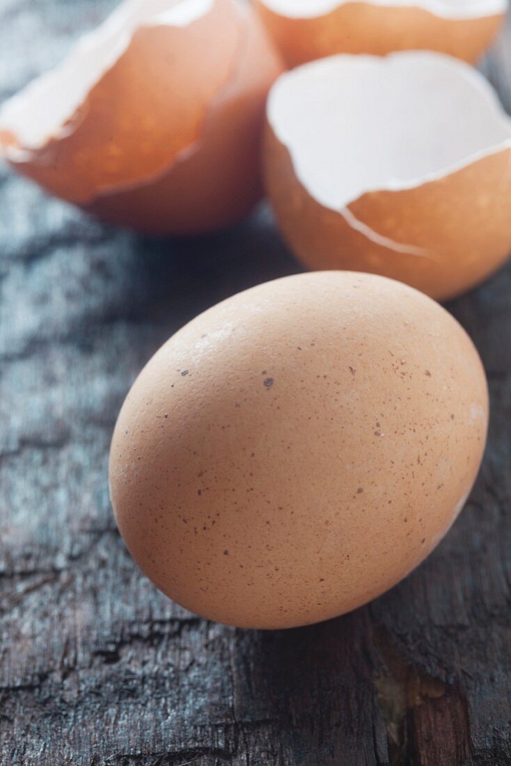 Rohes Ei und Eierschalen auf Holzuntergrund