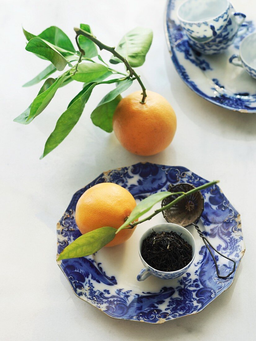 Orange Pekoe Schwarztee in einer Teetasse mit Teesieb und Orangen