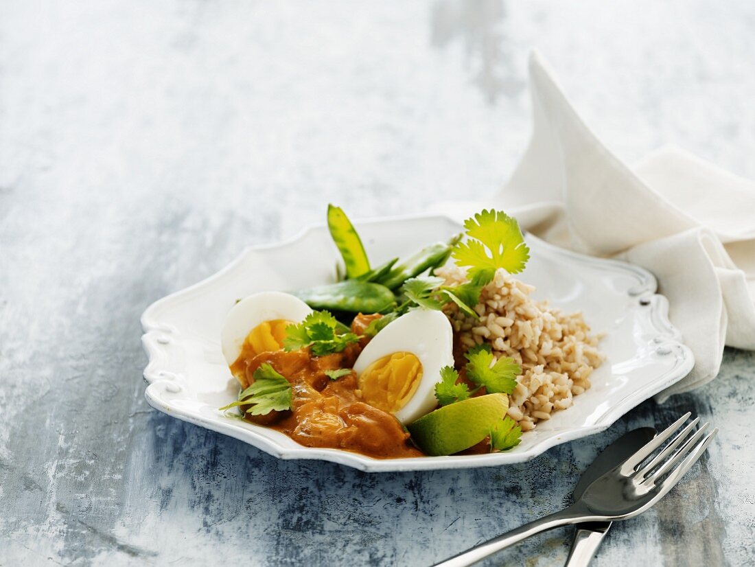 Indian curry with boiled eggs, dried apricots, rice and sugar snap peas