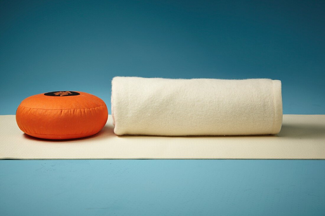 A cushion, a blanket and a yoga mat