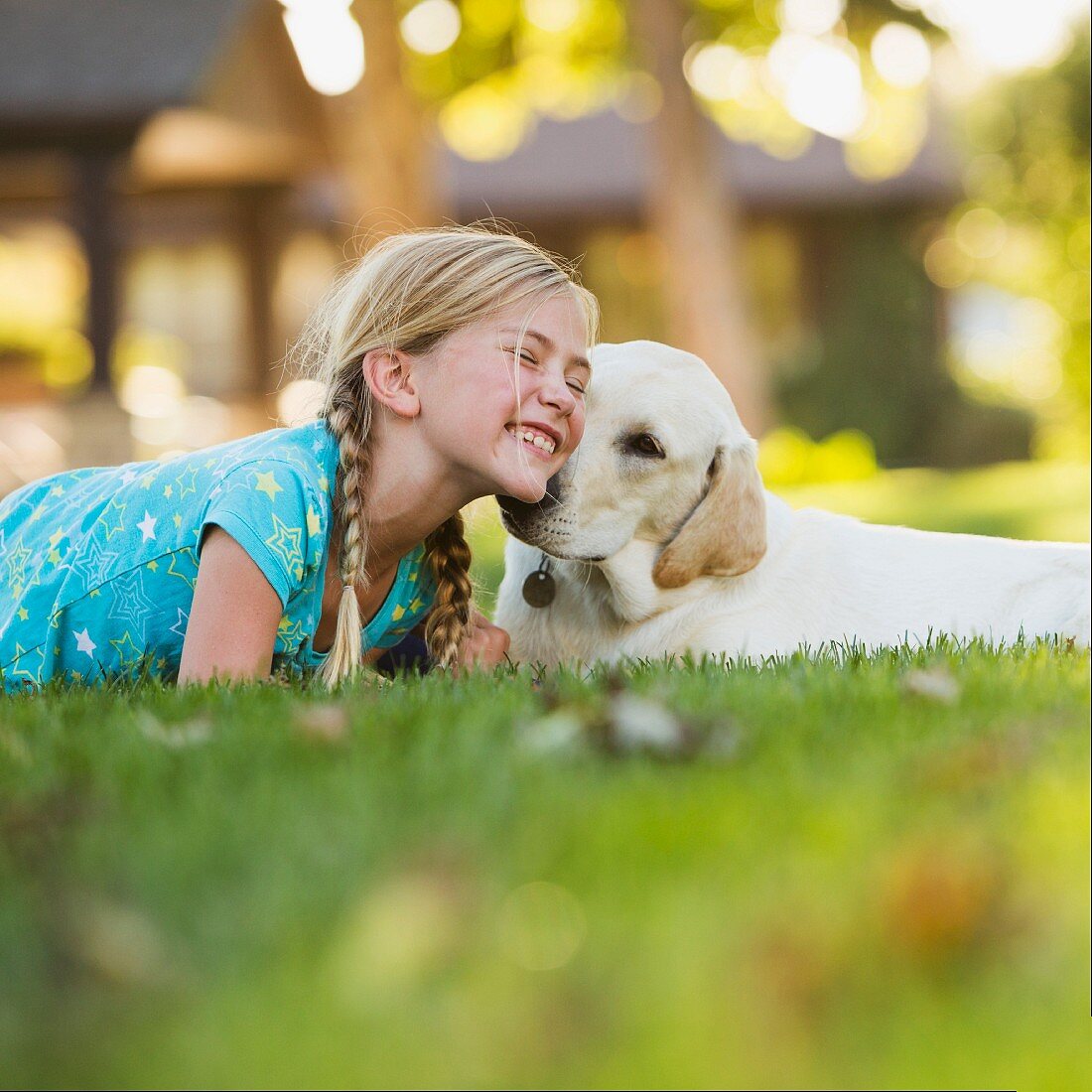 Girl and young dog lying on lawn