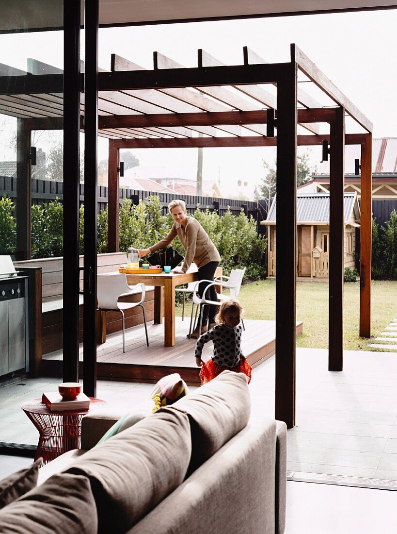 Holzterrasse mit Esstisch und Stühlen unter Pergola