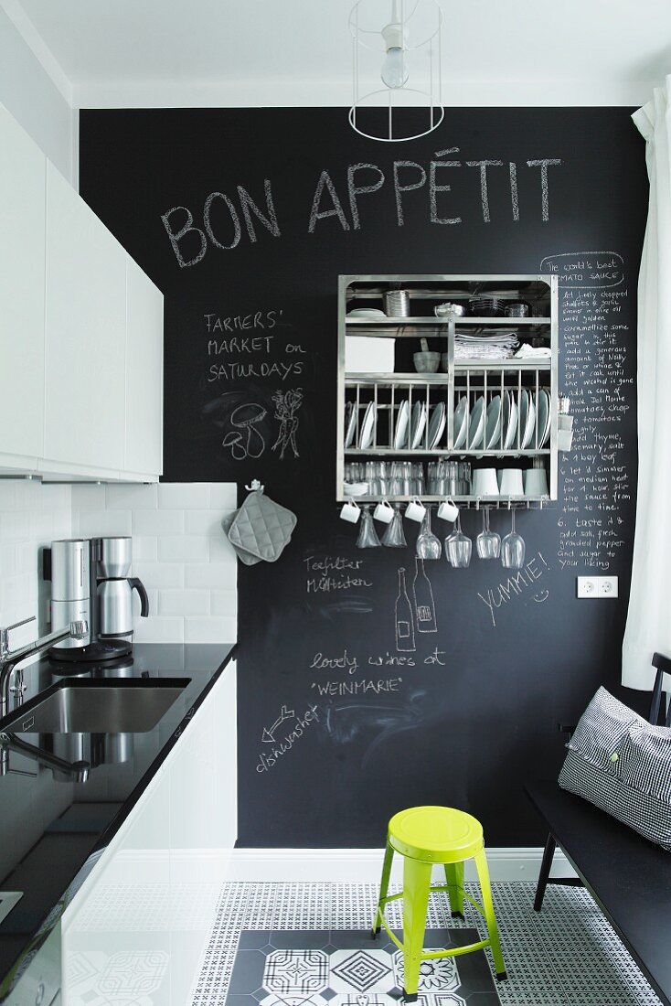 Kitchen with glossy fronts, decorative black and white floor tiles and chalkboard wall