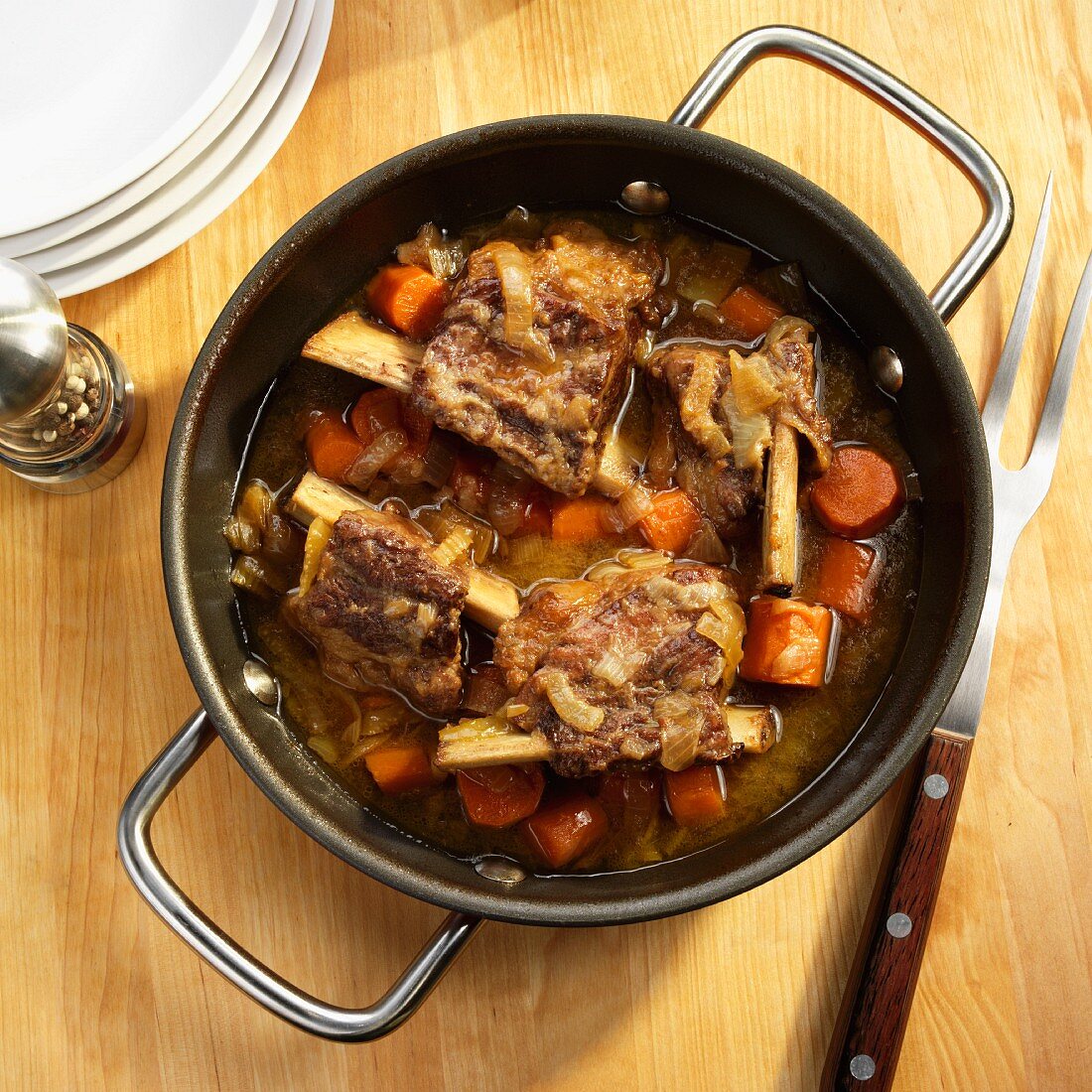 Beef ribs braised in beer with carrots, onions and celery in a pot