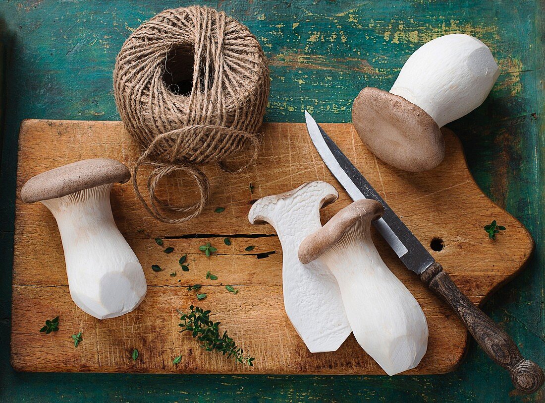 Fresh king trumpet mushroom on a chopping board with a knife and kitchen twine