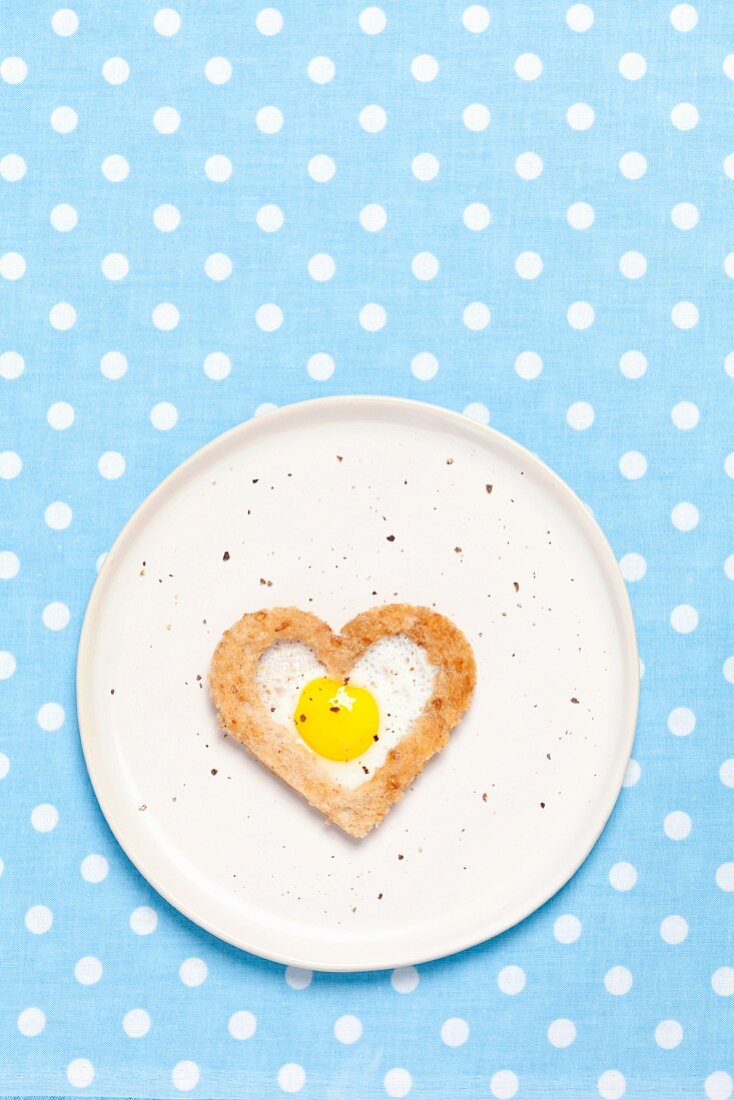 A fried quail's egg baked into a heart-shaped slice of toast