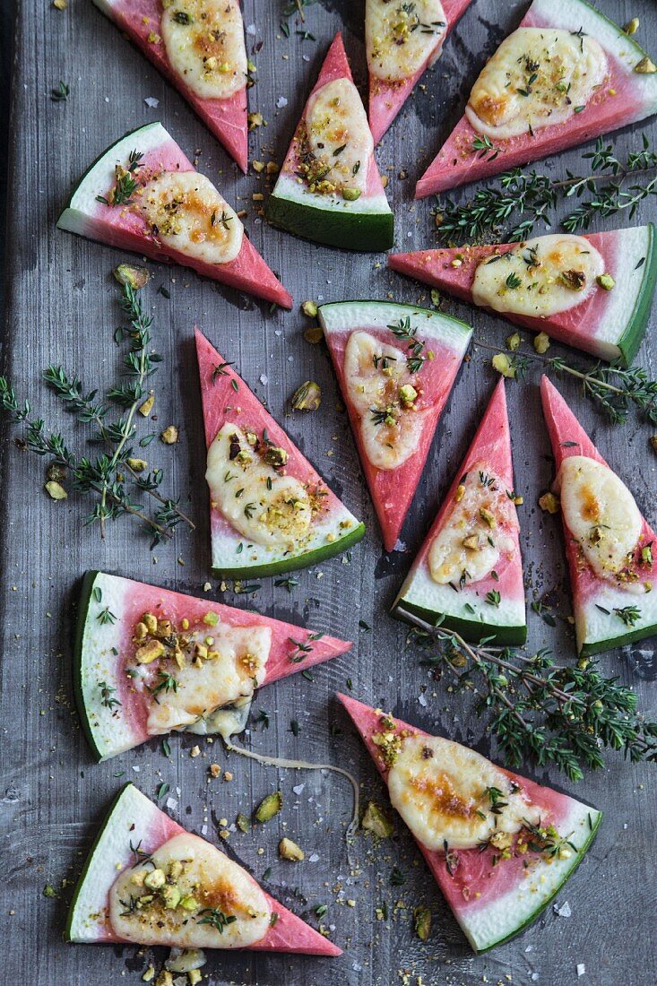 Gratinated watermelon slices with cheese, thyme and pistachios