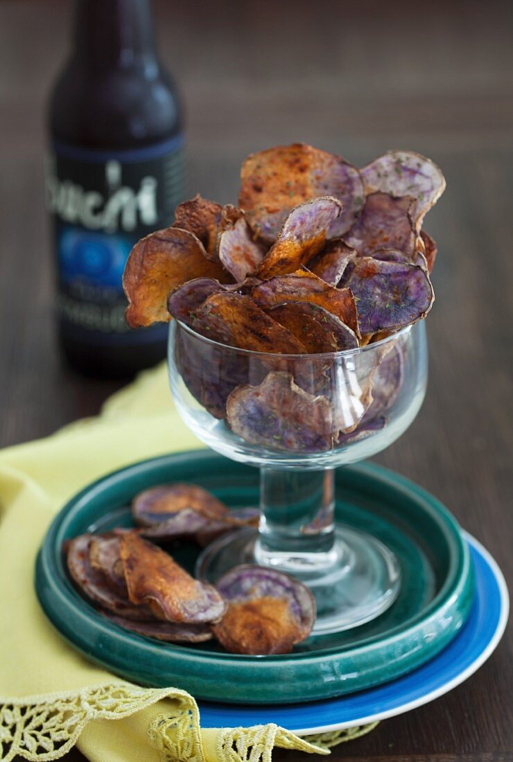 Lila Kartoffelchips im Glas vor Bierflasche