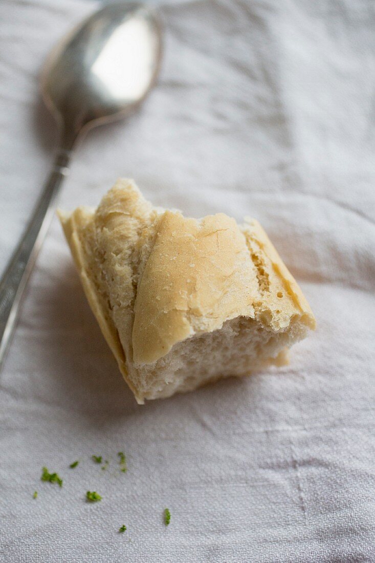 A piece of baguette with a spoon on a linen cloth