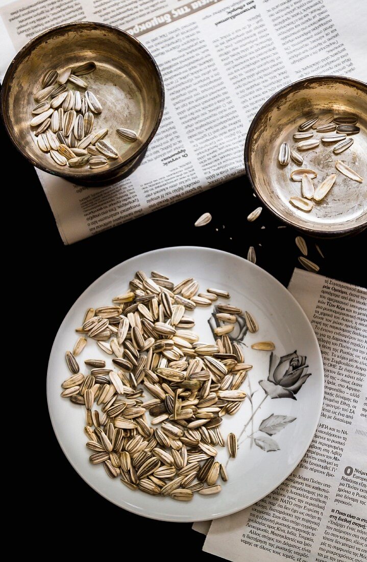 Sunflower seeds on a plate and in a bowl on a newspaper