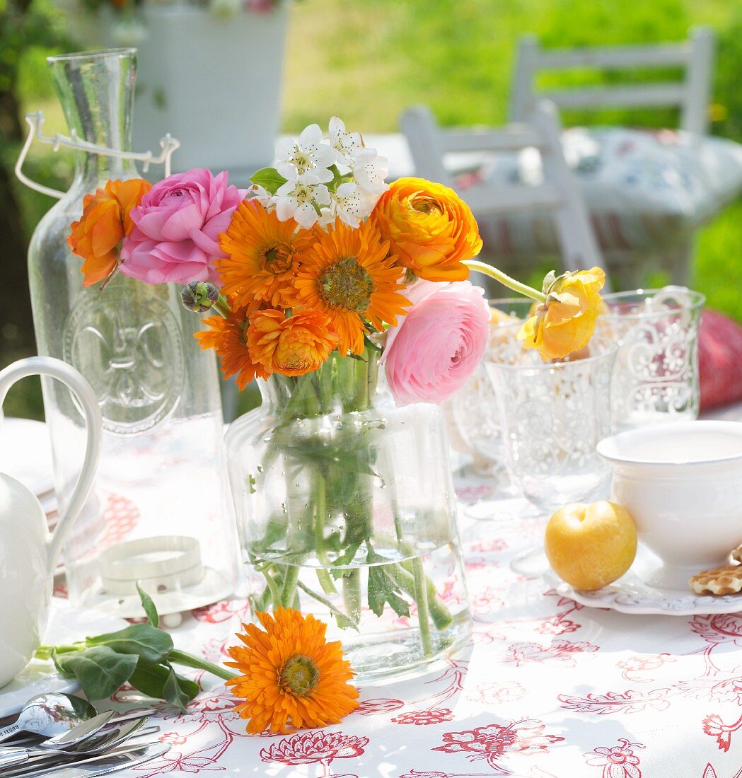 Kleiner Blumenstrauss in Retro Glasvase auf Tisch im Freien