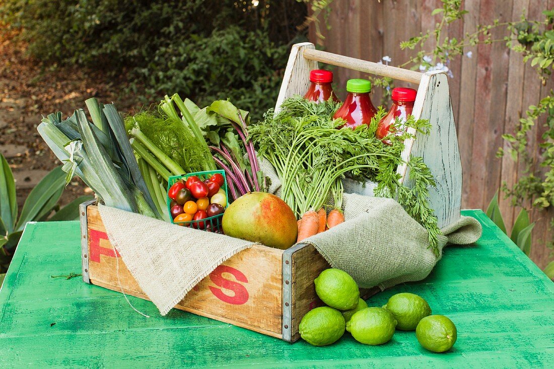 A wooden crate of fruit and vegetables on a rustic garden table