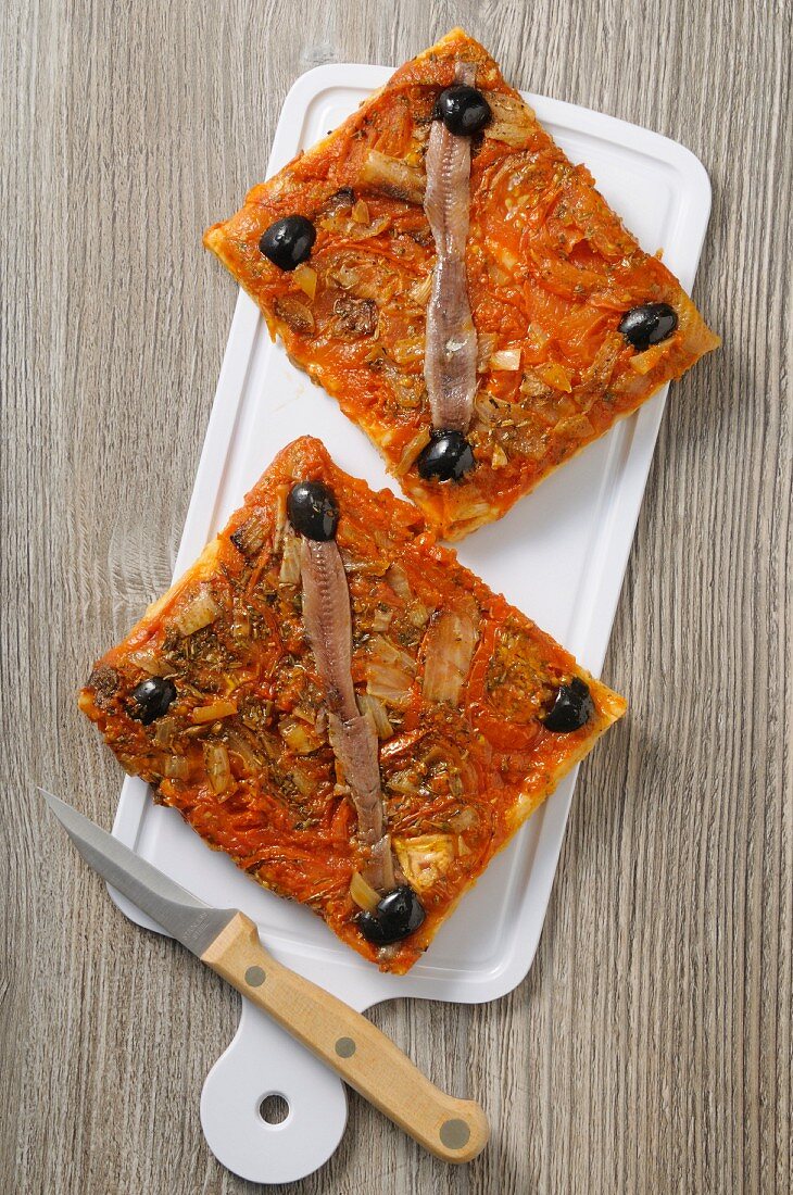 Two slices of pizza with anchovies and olives