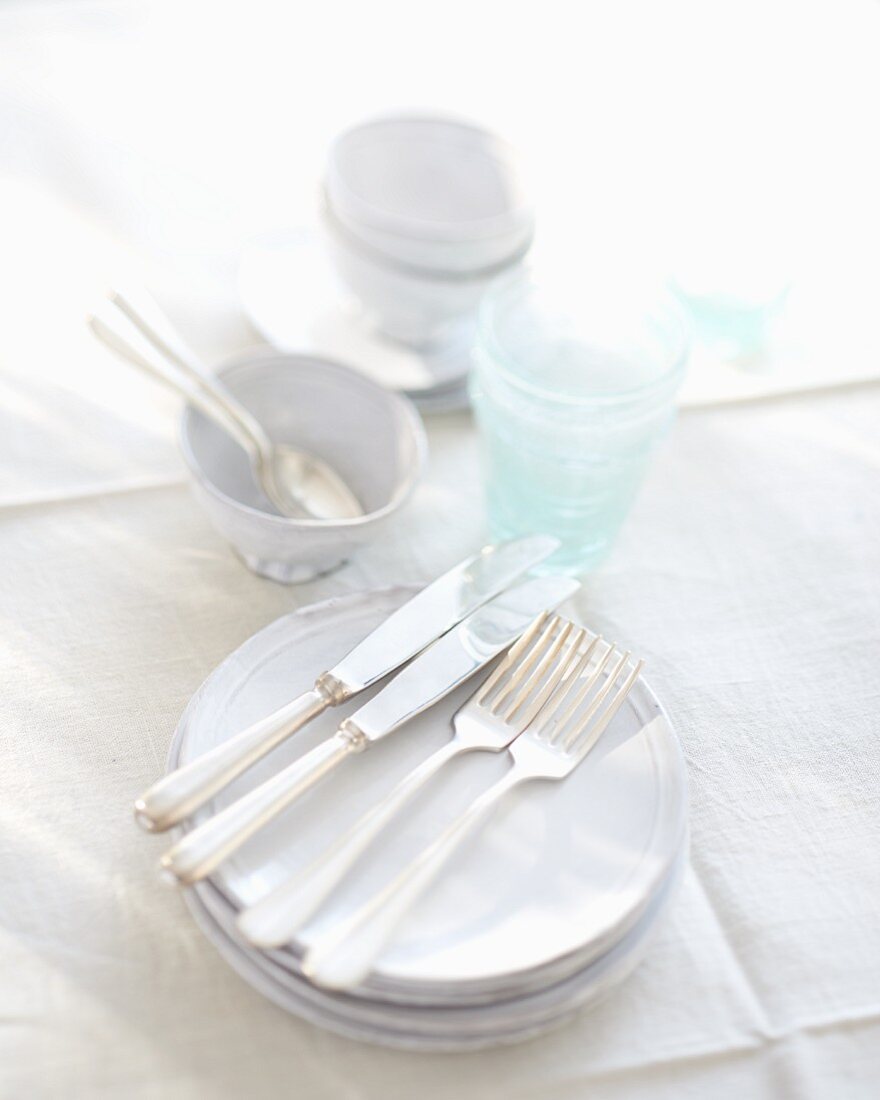 Weisses Geschirr und Gläser auf weisser Tischdecke