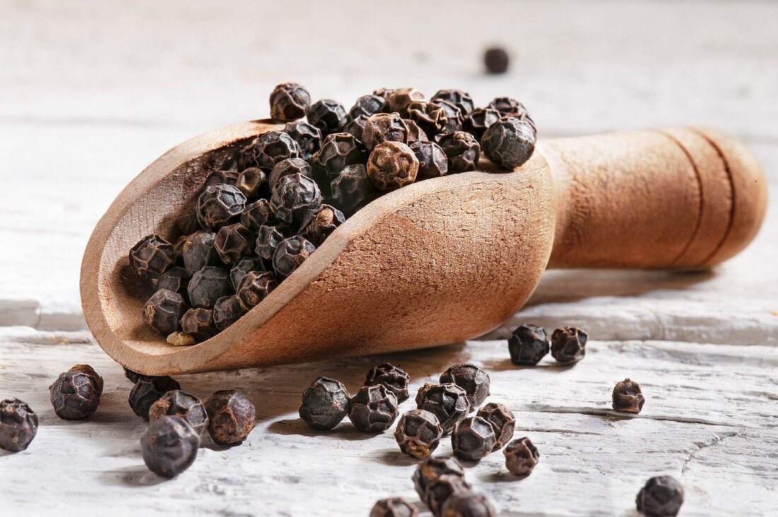 Black peppercorns in a wooden scoop