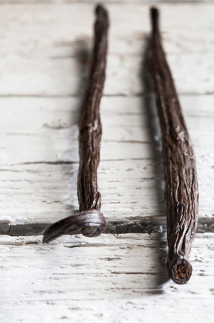 Three vanilla pods on a wooden surface