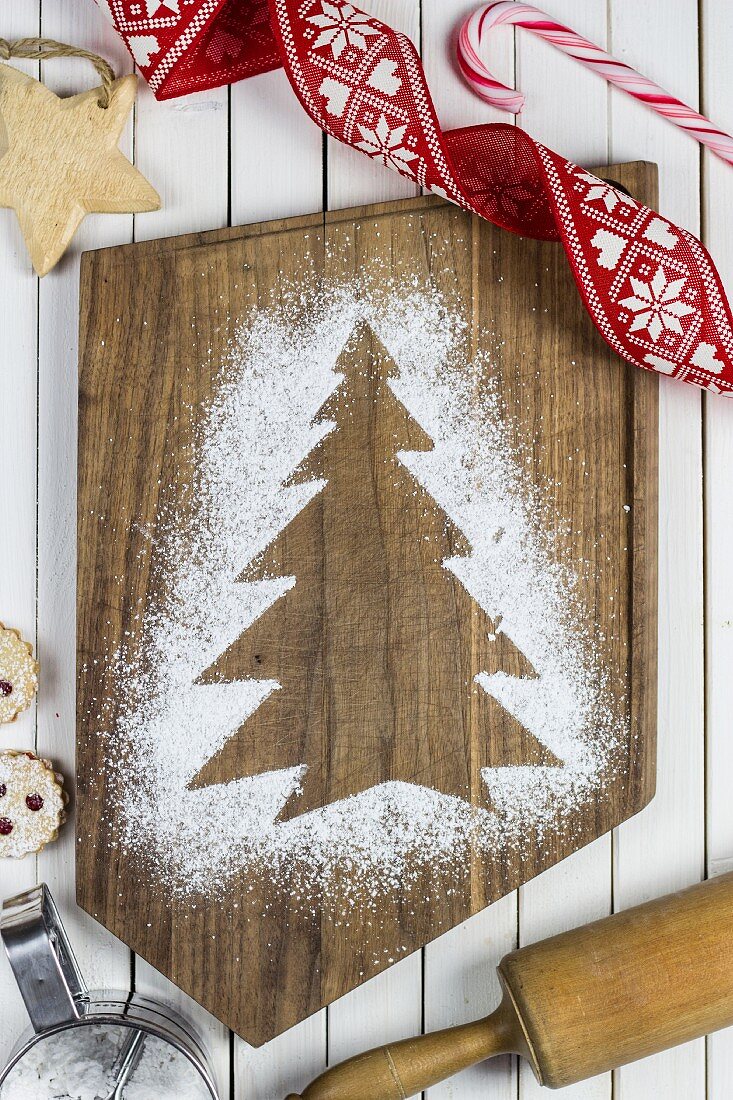 A Christmas tree print in icing sugar on a chopping board