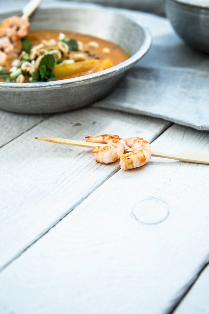 Cucumber curry with peanuts and prawn skewers