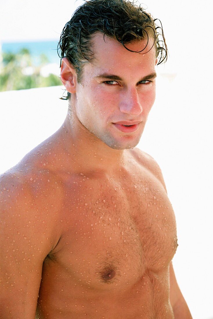 A young, sporty, topless man with wet hair